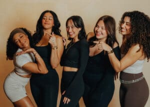 Group of six women in neutral athletic wear smiling together during Pilates branding photoshoot in Orlando studio.