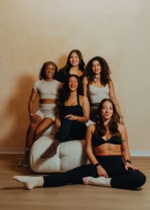 Group of six women in neutral athletic wear smiling together during Pilates branding photoshoot in Orlando studio.