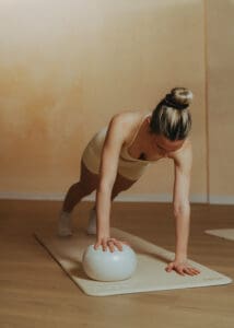 Pilates instructor holding plank position with exercise ball on mat, photographed for wellness branding session in Orlando studio.
