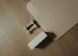 Minimalist wellness detail photo of Pilates mats, dumbbells, and yoga block arranged on wood floors inside Solace Studio.