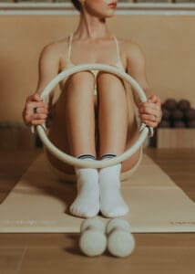 Pilates instructor performing reformer ring exercise on a mat inside a warm, neutral-toned Pilates studio in Orlando.