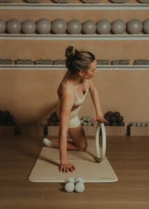 Pilates instructor performing reformer ring exercise on a mat inside a warm, neutral-toned Pilates studio in Orlando.