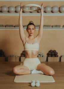 Pilates instructor performing reformer ring exercise on a mat inside a warm, neutral-toned Pilates studio in Orlando.