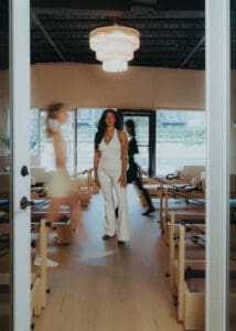 Pilates instructor standing between reformers while team members move in background, photographed for Solace Studio branding photography in Orlando.