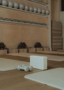 Minimalist wellness detail photo of Pilates mats, dumbbells, and yoga block arranged on wood floors inside Solace Studio.