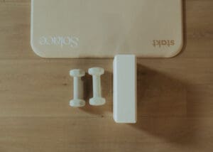 Minimalist wellness detail photo of Pilates mats, dumbbells, and yoga block arranged on wood floors inside Solace Studio.