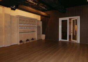 Wide interior photo of modern Pilates studio with reformers, neutral tones, and wood panel walls.