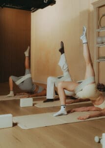 Group Pilates class performing synchronized core exercises on mats, photographed for fitness brand photography and studio marketing content.