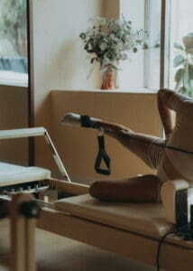Pilates instructor performing a reformer exercise near large windows at Solace Studio in Orlando, photographed with soft natural light for wellness brand photography.