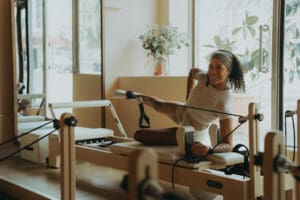 Pilates instructor performing a reformer exercise near large windows at Solace Studio in Orlando, photographed with soft natural light for wellness brand photography.