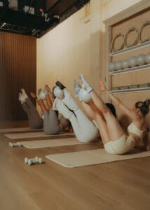 Group Pilates class performing synchronized core exercises on mats, photographed for fitness brand photography and studio marketing content.